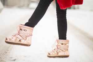 person wearing gold patent leather snow boots