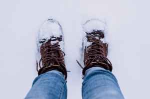 person wearing brown boots and blue denim jeans standing on snow